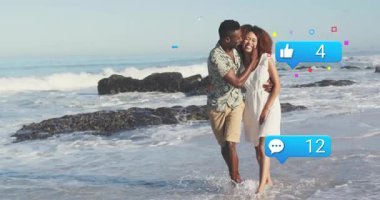 Çevrelerinde sosyal medya simgeleri oluşturan çiftler sahilde yürüyorlar. Nişan sayılarını arttırıyorlar. Romantik, boş zaman, kıyı, iletişim, bağlantı, mutluluk, yaşam tarzı