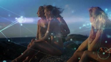 Gün batımında kaya kenarına yerleşen üç kadın parlayan düğümleri başlatıyorlar. Teknolojik çizgiler kahkahalar atıyor. Yoldaşlar, deniz kenarı, dijital, dinginlik, dostluk, rahatlık, coşku