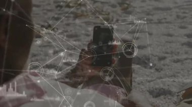 Adam plajda koyu renk akıllı telefon ekranını tıklatarak animasyon teknolojisi çizelgesi radyal nabız ölçümlerini izliyor. Teknoloji, yenilik, bağlantı, dijital, açık hava, boş zaman, modern