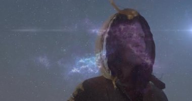 Kapüşonlu kadın yıldızlı gökyüzünde başını çeviriyor nebula oluşurken ve mercek parlarken gözleri parlıyor. Kozmik, mistik, fantezi, ruhani, göksel, gerçeküstü, atmosferik