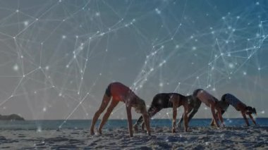 Yoga takımı sahile inerken köpek pozu vererek kalp atışları ile sağlık takibini sağlıyor. Spor, sağlık, dinginlik, uyum, bağlantı, farkındalık, açık hava.