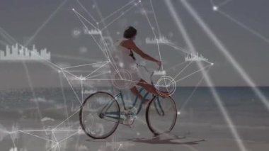 Kıyı şeridinde bisiklet süren ve hız kontrolü için tekerleklerin etrafını dijital olarak kaplayan bir kadın. Açık hava, seyahat, yenilik, teknoloji, eğlence, doğa, bağlantı