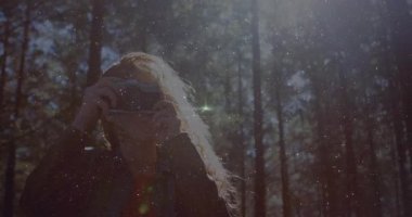 Kadın fotoğrafçı, kamera kaldırıyor ve ormanı güneş ışığını yakalamak için yeşil mercekli çerçeveliyor. Doğa, vahşi doğa, keşif, açık hava, manzara, dinginlik, macera