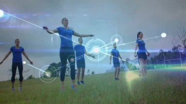 Tepede altı fitness sınıfı kollarını kaldırıyor, parlayan düğümleri aydınlatıyor ve hareket ağını geliştiriyor. Egzersiz, bağlantı, hareket, takım çalışması, açık hava, teknoloji, uyum.