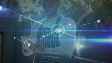 Erkek aşçı verandada tablet aşırıyor ve göğüs kafesinde büyüyen bir aşçılık teknolojisi ağı oluşturuyor. Teknoloji, bağlantı, yenilik, dijital, profesyonel, açık hava, modern