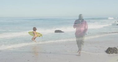 Haberler için mikrofona konuşan bir muhabir, sörf tahtası tutan ve sahilde dalgalanan bir sörfçü. Gazetecilik, kıyı, macera, açık hava, iletişim, yaşam tarzı, dinamik