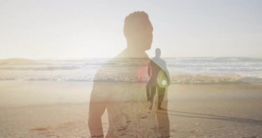 Seyahat reklamı, güneşli plajda solup giden arkadaşlarını gösteriyor. Sörf tahtası yaklaşıyor. Macera, yoldaşlık, eğlence, sahil, gün batımı, canlılık, açık hava