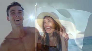 Rüzgar, kadınların hasır şapka ayarlamasına, erkeklerin gülmesine, bayrak sallamasına yol açıyor. Romantik, deniz kenarı, boş zaman, yaz, sıcaklık, mutluluk, kutlama