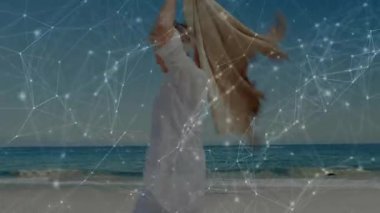 Kıdemli kadın elinde katlanmış şalla kumsalda sarıp dijital ağ örtüsünü ortaya çıkarıyor. Zarif, dinginlik, farkındalık, rahatlama, sofistike, manzaralı, düşünceli.