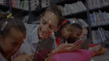 Öğretmenlerin tabletleri tıklaması, öğrencilere cihaz dağıtması, kitaplıkların yanında eğitim kitaplarına rehberlik etmesi. Eğitim, sınıf, teknoloji, okur yazarlık, öğrenme, çeşitlilik, etkileşimli