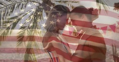 Çift bakışları, alacakaranlık kumsalında yaklaşırken bayraklar hayat tarzında öpüşmeye hazırlanıyor. Romantizm, şefkat, günbatımı, samimiyet, kutlama, eğlence, uyum.