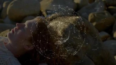 Gün batımında çakıl taşlarına uzanmış uzanmış bir kadın ve ortaya çıkan bir veri küresi kafasının etrafında menekşe ışıltısı saçıyor. Teknoloji, yenilik, bağlantı, fütürizm, dinginlik, farkındalık, dijital sanat