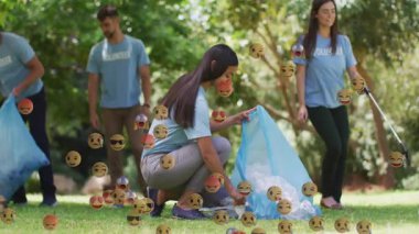 Gönüllü ekip güneş parkından çöp topluyor, yüzen emoji simgeleri yeşil temizliği gösteriyor. Topluluk, çevre, çevre dostu, koruma, takım çalışması, açık hava, canlı