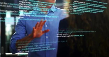 Adam, Palm 'ı cam panele doğru getiriyor holografik kodu takip ediyor ve iş arkadaşına mantığı anlatıyor. Futuristik, işbirliği, yenilik, teknoloji, dijital, takım, profesyonel