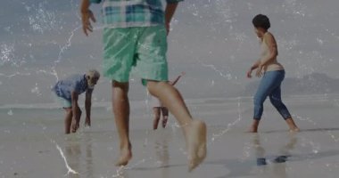 Sağlık reklamı çerçeveye çarpan çocuğu, çömelmiş aileyi kıvılcımlar kıvılcımlar saçarak kum egzersizinde suyu tekmelerken gösteriyor. Sahil, eğlence, neşe, yansıma, açık hava, aile bağı, canlı