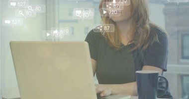 İçerik yaratıcısı yazı yazarken dizüstü bilgisayarın yanında yüzen animasyon simgelerini izliyor. Teknoloji, çalışma alanı, minimalist, dijital, iletişim, profesyonel, kentsel