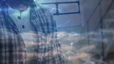 Erkek öğrenci akıllı telefon ekranını dinliyor ve çalışırken teknoloji bulut ağı örtüsünü etkinleştiriyor. Teknoloji, dijital, iletişim, bağlantı, yenilik, fütürizm, modernite