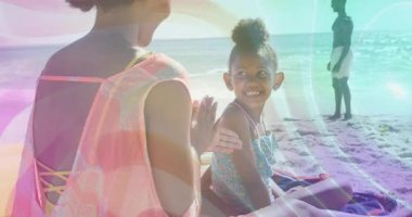 Anne plajda güneş kremi sürüyor ve cilt koruması için kızının omuzlarına yayılıyor. Aile, sahil, güneş kremi, sahil, açık hava, boş zaman, güneş ışığı.