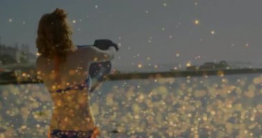 Yüzücü, kafasının üstünde dalış kıyafeti tutuyor Alacakaranlık Koyu 'nda Bokeh' le su sporu yapmak için elbiseyi indiriyor. Sahil, sahil, deniz, dinlenme, sükunet, günbatımı, minimalizm