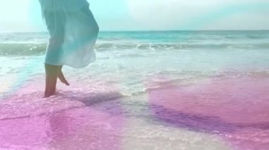 Kumlu sahil şeridinde sığ pembe sörf yapan, dans eden, seyahat reklamı için su sıçratan bir kadın. Deniz, sahil, boş zaman, akışkan, zarif, canlılık, açık hava.