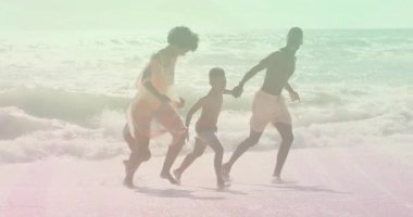 Aile sığ dalgalara giriyor ve güneş ışığı altında sağlıklı yaşam için kumlu kıyı şeridi boyunca koşuyor. Aile, kumsal, macera, birliktelik, hareket, açık hava, canlılık