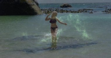 Kaldıran el, sığ turkuaz suya atlayan ve seyahat terfisi için su sıçratan kız. Kumsal, çocuklar, neşeli, canlı, açık hava, boş zaman, manzaralı