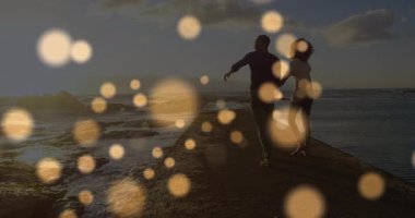 Bir çift yürüyen taş iskelenin orta noktasına ulaşması, altın ışıkların seyahat için ufuk çizgisini göstermesine neden oluyor. Romantik, günbatımı, sükunet, deniz kenarı, siluet, rahatlık, manzara