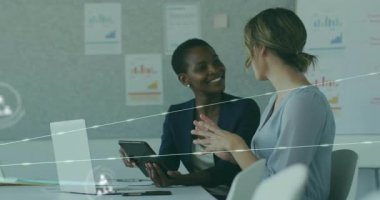 İki profesyonel kadın ortak veri incelemesi için teknik toplantıda tablet kullanıyor. Ağ simgeleri canlandırılıyor. İşbirliği, takım çalışması, veri görselleştirme, dijital ağ, profesyonel tartışma, yenilik, kurumsal ortam