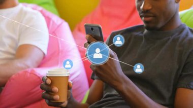 Elinde kahve fincanı tutan adam akıllı telefonu çalıştırarak sosyal ağ simgelerini genişletiyor. Günlük, ağ kurma, iletişim, dinlenme, arkadaşlık, bağlantı, modern