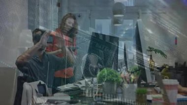 VR kulaklık takan ve teknoloji grafiklerini değiştiren bir adam iş arkadaşının tableti izlediği eğilimleri analiz ediyor. Gelecek, yenilik, işbirliği, dijital, teknoloji, dinamik, ofis