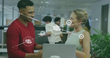 Adam dizüstü bilgisayarı tıklatıyor, kadın teknoloji ofisinde başını sallıyor yumurtluyor ve küresel veri simgelerini genişletiyor. İşbirliği, takım çalışması, yenilik, dijital, bağlantı, ağ, iletişim