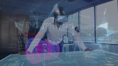 Olgun bir adam şirket masasında VR kulaklık takıyor, 3D verileri analiz ediyor ve iş arkadaşının tabletini tıkırdatıyor. Teknoloji, yenilik, işbirliği, fütürizm, dijital, kurumsal, dalgın