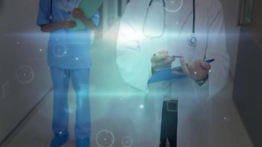 Hologram bulanıklığı, sağlık ekibinin koridora girip steteskop ve grafiklerin etrafında döndüğünü gösteriyor. Tıbbi, sağlık, teknoloji, profesyonel, takım çalışması, yenilik, temiz