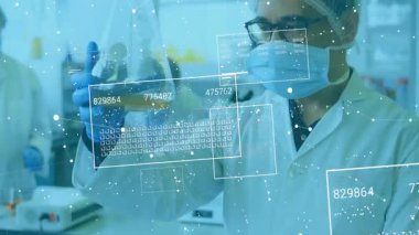 Laboratuvarda kehribar rengi sıvı matarayı tutan erkek bilim adamı kehribar örneğini analiz eden veri panellerini çalıştırıyor. Bilim, yenilik, teknoloji, analiz, araştırma, deneysel, geleceksel