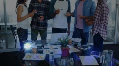 Ofis toplantısında cam masanın etrafında toplanan ekip işaretleri seçip cihazlarla ilgili fikirleri paylaşıyor. İşbirliği, beyin fırtınası, takım çalışması, yenilik, profesyonel, modernlik, dijital araçlar