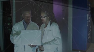 Laboratuar araştırmacıları veri merkezinde veri analizi başlatıyorlar. Ağ atımları dizüstü bilgisayarın etrafında dönüyor. Teknoloji, yenilik, siber güvenlik, dijital, bağlantı, analitik, bilim