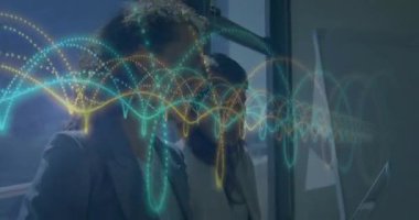 İki kadın çift monitörleri izliyor ve iş verilerini gösteren parlayan dalga şeklinde kavisler yaratıyor. Gelecekçi, yenilikçi, teknoloji, şirket, işbirliği, gösterişli, enerjik