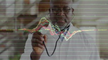 Kıdemli doktor, hayati verileri gösteren tıbbi dalga biçimini etkinleştirirken dürbünü döndürerek tutuyor. Sağlık, tanı, teknoloji, veri görselleştirme, klinik, profesyonel, tıbbi ekipmanlar