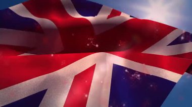 Rüzgâr şiddetlenen Union Jack bayrağı güneş altında dalgalanırken ışık parçacıkları kıvrılmaya başlar. Vatanseverlik, milliyetçilik, açık hava, kumaş, hareket, güneş ışığı, kutlama