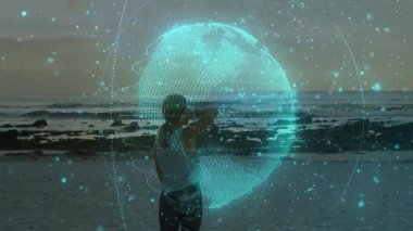 Gün batımında plajda ortaya çıkan teknoloji küresiyle etkileşime giren bir kadın küresel veri görselleştirmesini keşfediyor. Gelecek, yenilik, bağlantı, dinginlik, zarafet, manzara, teknoloji