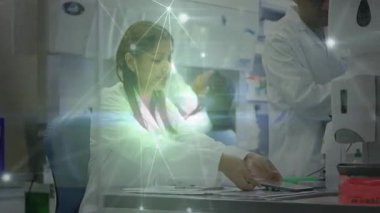 Meslektaşı örnek yüklerken, kadın laboratuar bilimcisi tablet başlangıç kaplamasını kullanarak slaytları sıralıyor. Bilim, yenilik, teknoloji, işbirliği, araştırma, dijital, kesinlik