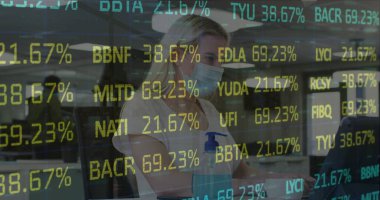 Yüz maskesi takan bir kadın açık ofiste dizüstü bilgisayarda el dezenfektanı ile piyasa saatlerini okuyor. Profesyonel, teknoloji, modern, kurumsal, sağlık, üretkenlik, güvenlik