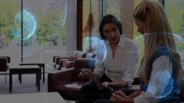 İşletme sunucusu dönen küreleri ve iş ortaklığı grafiklerini gösteren tableti tıklatıyor. İşbirliği, yenilik, teknoloji, kurumsal, profesyonel, fütüristik, iletişim