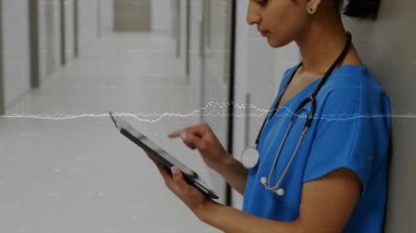 Hemşire tablet ekranını hastane koridorundaki hasta verilerini takip ediyormuş gibi gösteriyor. Tıbbi profesyonel, sağlık hizmeti, dijital cihaz, teknoloji, klinik, tanı, modern
