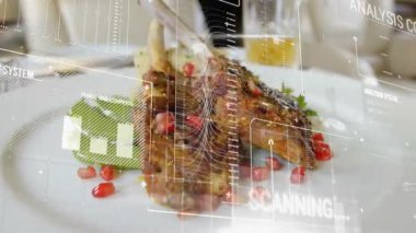 Metal maşalar kuzu kemiklerini ayarlar yemek taramasını başlatır sonra da kamera tepsiyi geri çeker. Gurme, aşçılık, sunum, modern, duyarlılık, iyi yemek, teknoloji