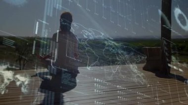 Yetişkin bir kadın avuçlarını dizlerinin üstüne koyup dünya haritası ve veri tablolarını gösteren teknolojiyi çalıştırıyor. Meditasyon, sükunet, bağlantı, dijital, manzara, doğa, farkındalık