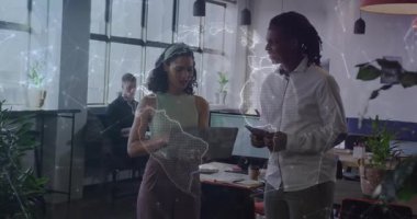 İş verileri analizini tartışan meslektaşlar, cihazlar üzerinde kıtaları döndüren holografik haritayı ateşliyor. İşbirliği, teknoloji, yenilik, dijital, iletişim, çalışma alanı, modern