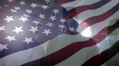 Beyaz yıldızlar, klinikteki maskeli sağlık görevlilerinin üzerinde dalgalanarak ABD bayrağını dalgalandırıyor. Sabır, adanmışlık, takım çalışması, profesyonellik, esneklik, birlik, modern