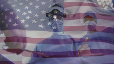 Cerrah kıskacı kavrayıp kesiyor, sonra dikiş atıyor ve asistanı bayrak kaplaması altında geri çekiliyor. Ameliyat, ameliyat, tıbbi, sağlık, takım çalışması, hassasiyet, kısır