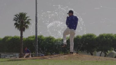 Beyzbol atıcısı ağırlık değiştiriyor, ön dizini kaldırıyor ve antrenmanda tam atış hareketi yapıyor. Atletizm, spor, eğitim, dinamik, açık hava, rekabet, takım çalışması